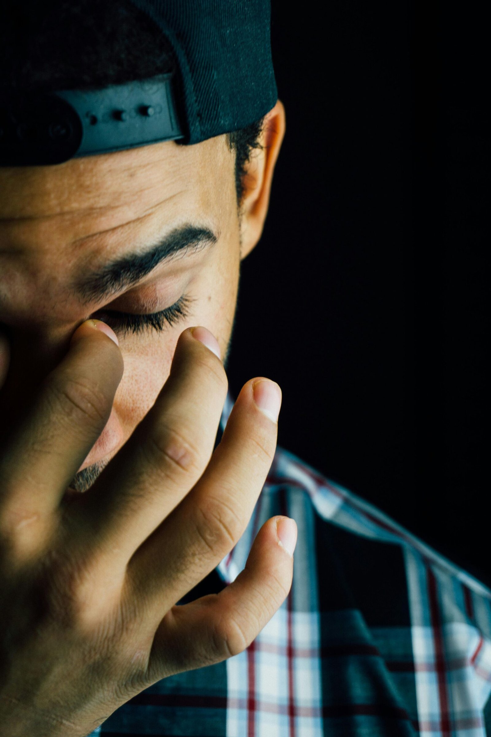 A close-up portrait capturing the emotional expression of a man in a dark studio setting.